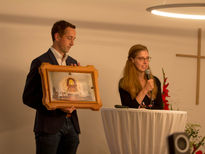 Ellen & Tobias zeigen das Heiligtumsfoto mit vielen Passfotos dahinter